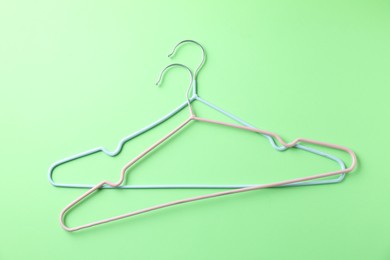 Photo of Two hangers on light green background, top view