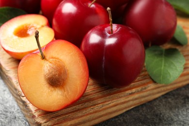 Photo of Fresh ripe cherry plums on wooden board, closeup