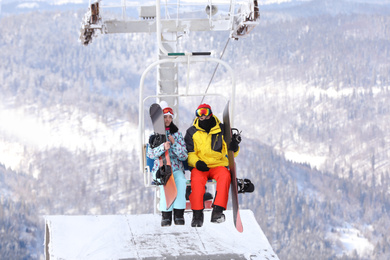 Photo of Couple using chairlift at mountain ski resort. Winter vacation