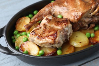 Tasty cooked rabbit with vegetables in baking dish on grey table, closeup
