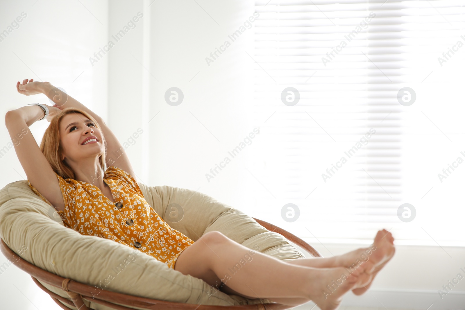 Photo of Young woman relaxing in papasan chair near window at home. Space for text