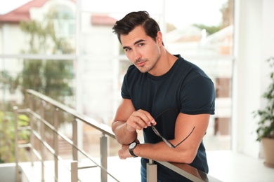 Photo of Portrait of handsome young man leaning on railing indoors