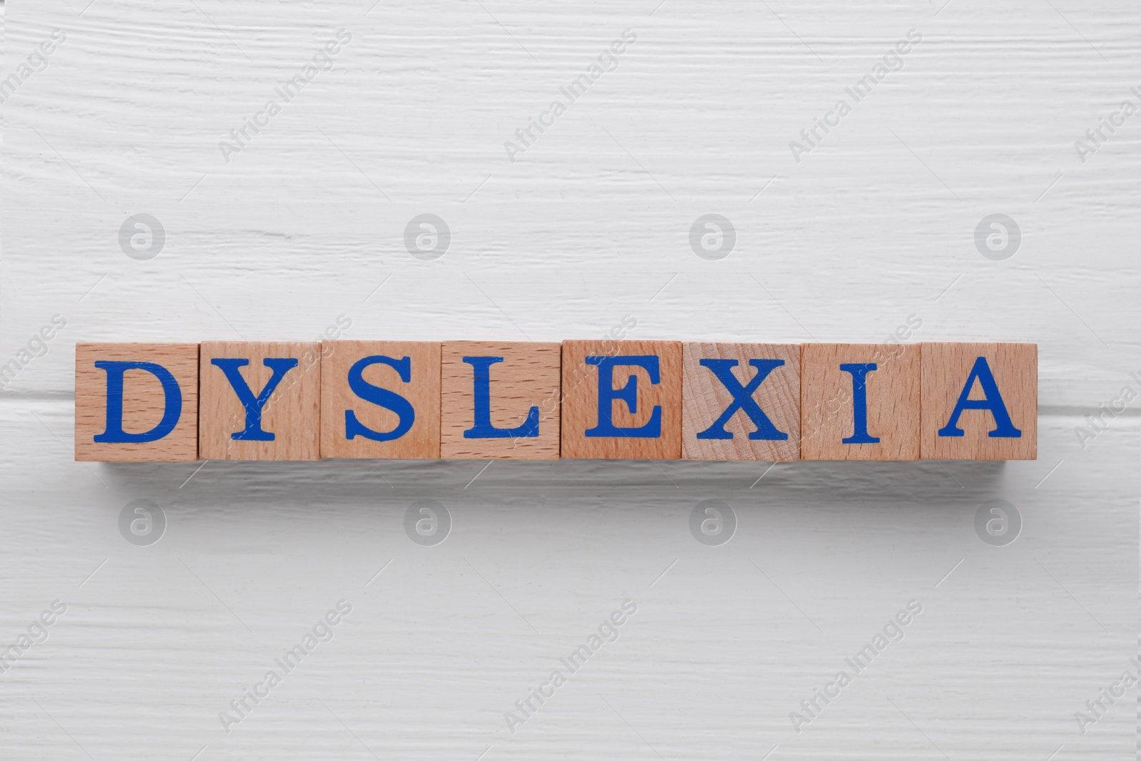 Photo of Cubes with word Dyslexia on white wooden table, flat lay