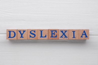 Photo of Cubes with word Dyslexia on white wooden table, flat lay