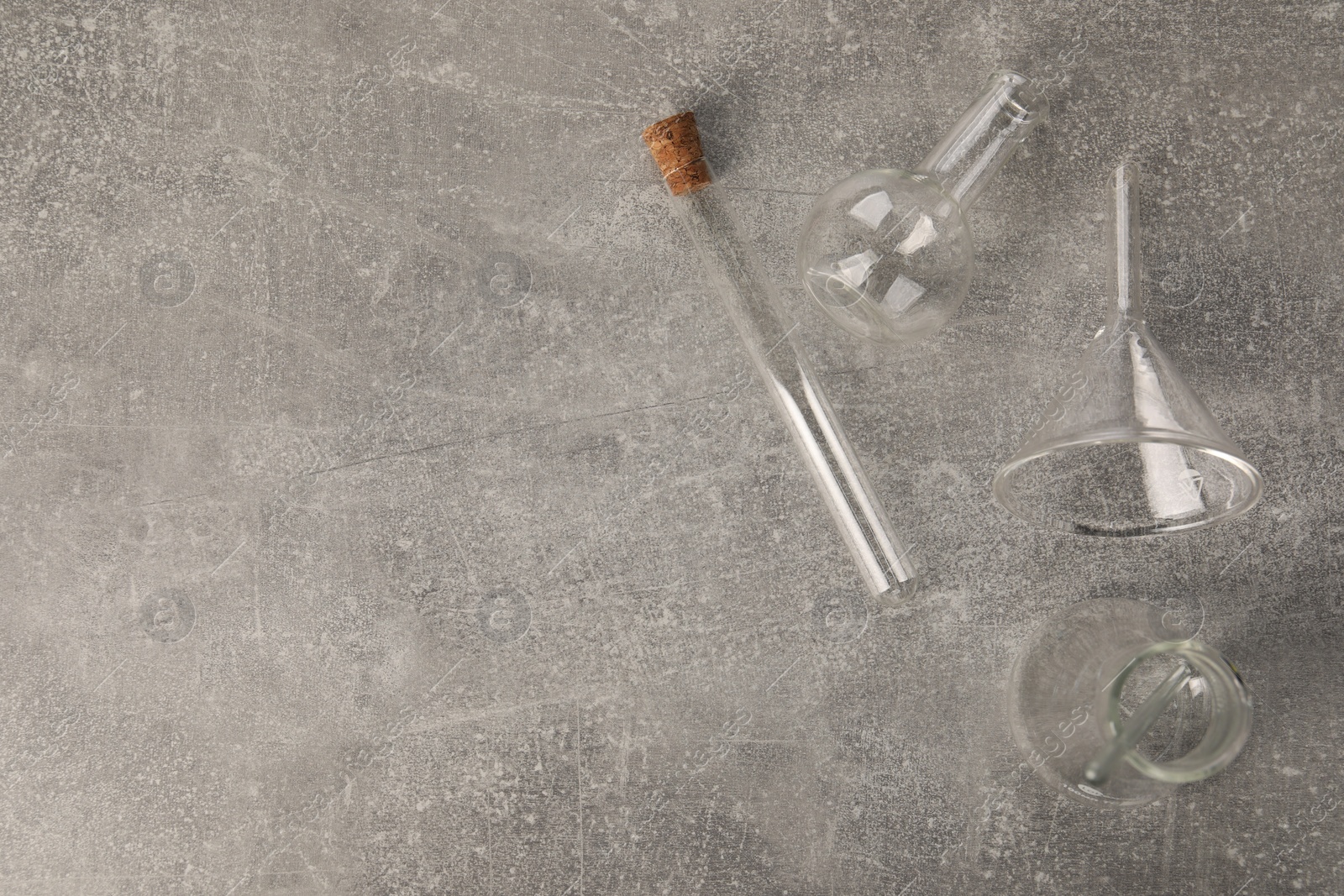 Photo of Different laboratory glassware on grey textured table, flat lay. Space for text