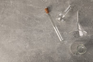 Different laboratory glassware on grey textured table, flat lay. Space for text