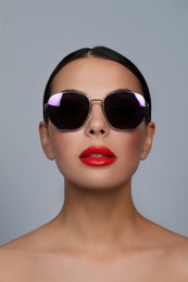 Photo of Attractive woman in fashionable sunglasses against grey background