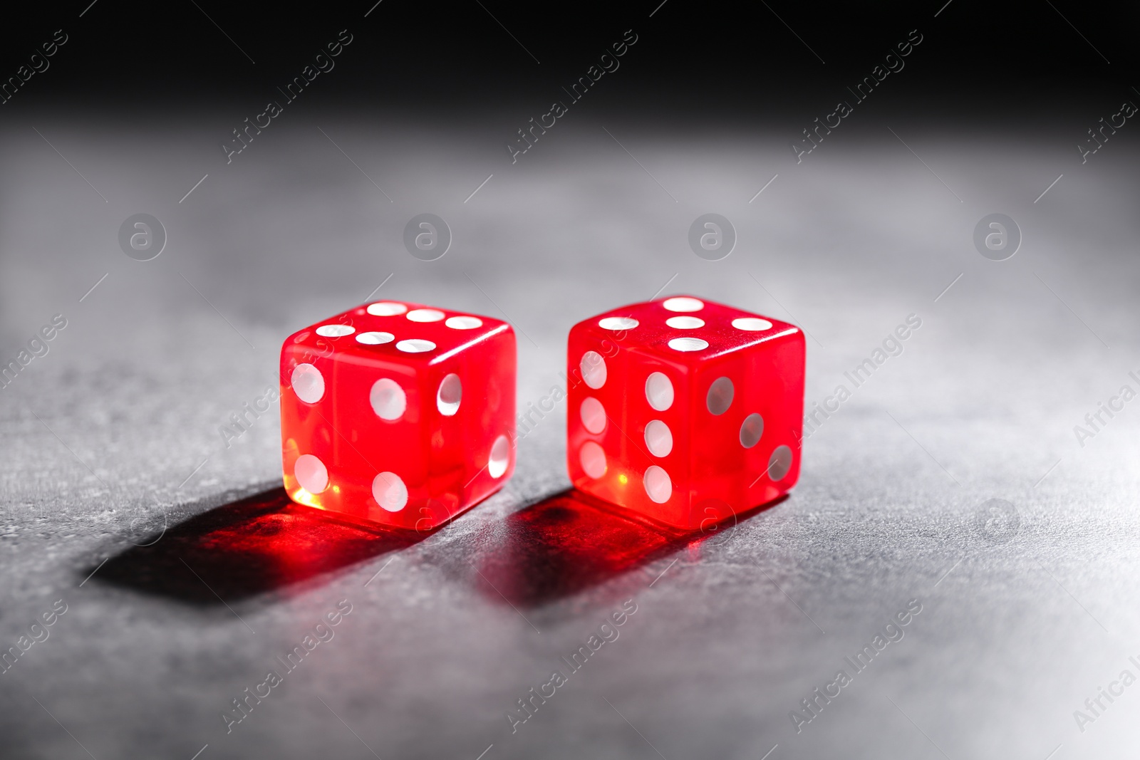 Photo of Two red game dices on grey textured table, closeup