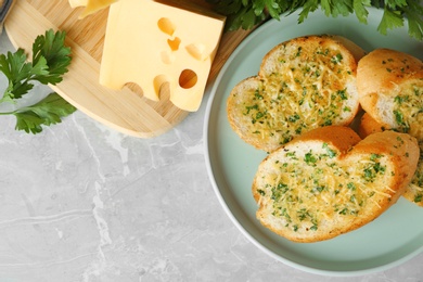 Photo of Slices of toasted bread with garlic, cheese and herbs on grey table, flat lay. Space for text