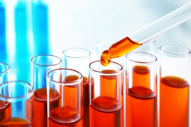 Photo of Dropping sample into test tube with orange liquid, closeup