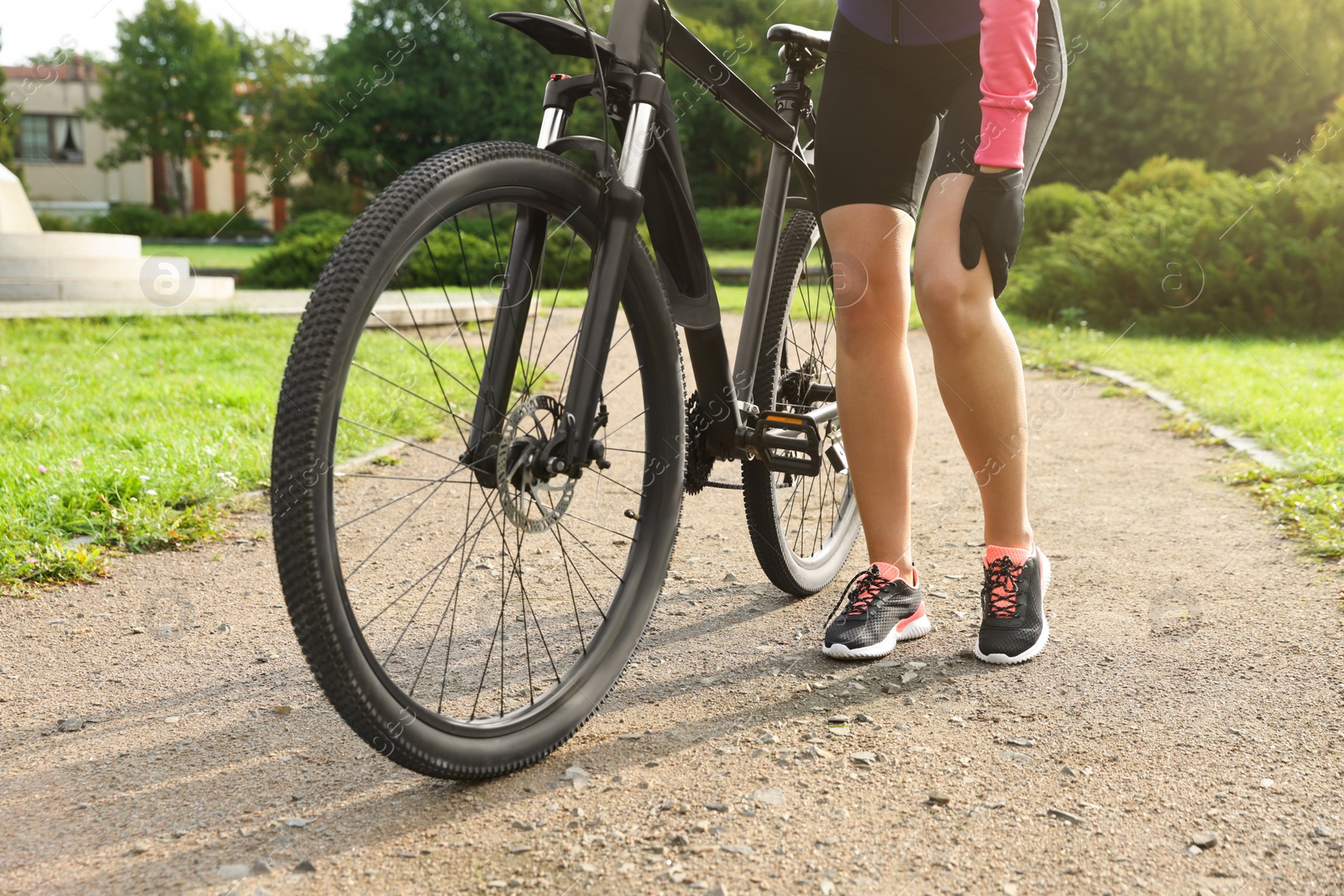 Photo of Woman with injured knee and bicycle outdoors, closeup