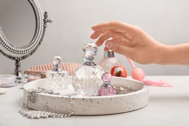 Photo of Woman reaching for crystal bottle of luxurious perfume on dressing table, closeup