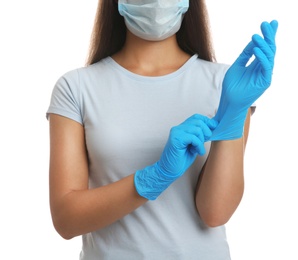 Woman in protective face mask putting on medical gloves against white background, closeup