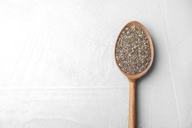 Photo of Spoon with chia seeds on light background, top view. Space for text