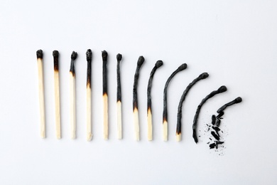 Photo of Row of burnt matches on white background, top view. Human life phases concept