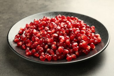 Ripe juicy pomegranate grains on grey table, closeup