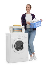 Beautiful young woman with laundry basket near washing machine on white background