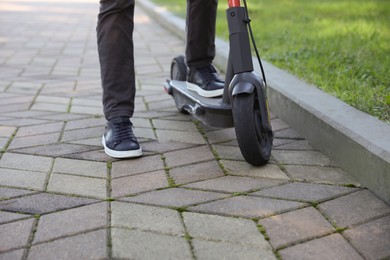 Photo of Man riding modern electric scooter in park, closeup