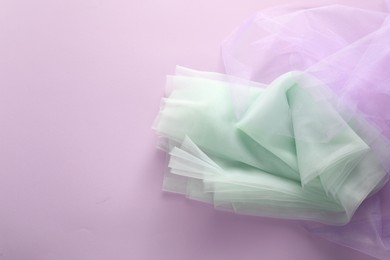Beautiful tulle fabric on lilac background, flat lay. Space for text