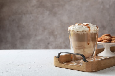 Glass of tasty caramel macchiato on table, Space for text