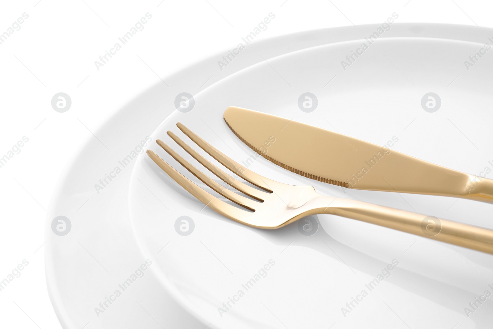 Photo of Stylish shiny cutlery and plates on white background, closeup