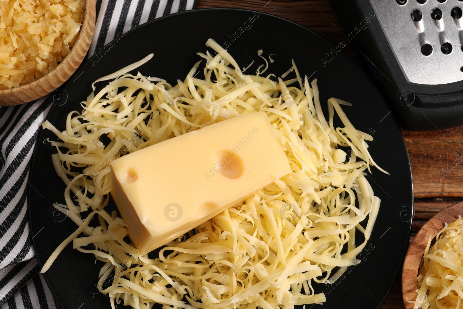 Photo of Grated and whole piece of cheese on wooden table, flat lay