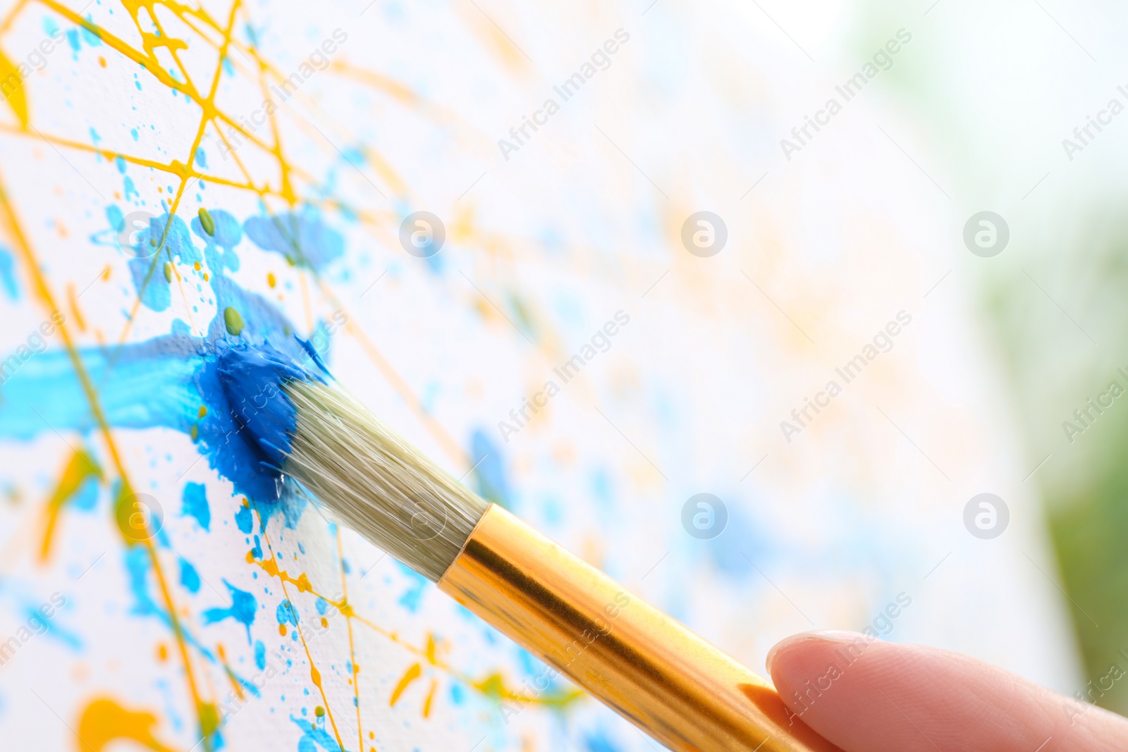 Photo of Artist painting on canvas with brush, closeup