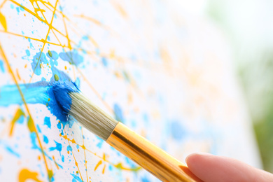 Photo of Artist painting on canvas with brush, closeup