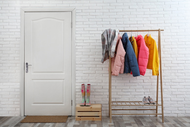 Wooden rack with stylish warm jackets in hallway