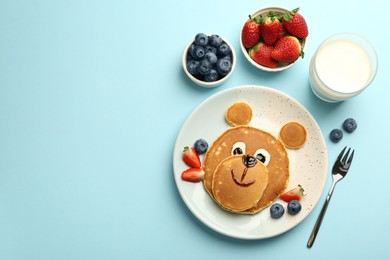 Photo of Creative serving for kids. Plate with cute bear made of pancakes and berries on light blue table, flat lay. Space for text