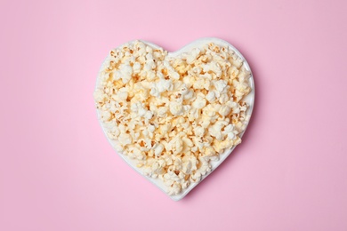 Plate with tasty popcorn on color background, top view