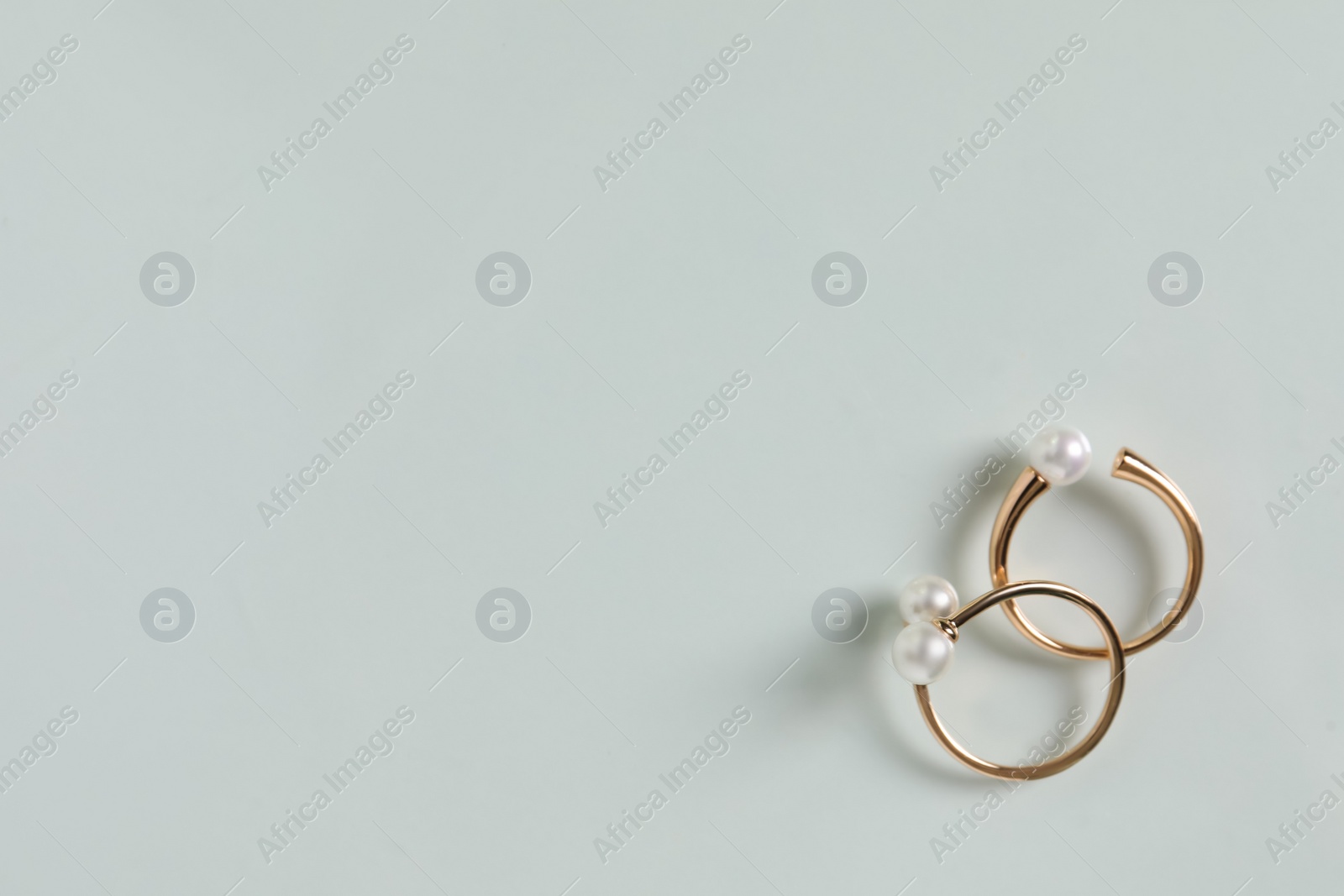 Photo of Elegant golden rings with pearls on white table, flat lay. Space for