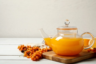 Photo of Delicious sea buckthorn tea and fresh berries on white wooden table. Space for text