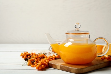 Delicious sea buckthorn tea and fresh berries on white wooden table. Space for text