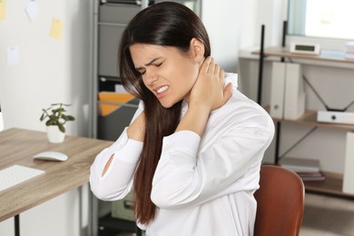 Photo of Young woman suffering from neck pain in office