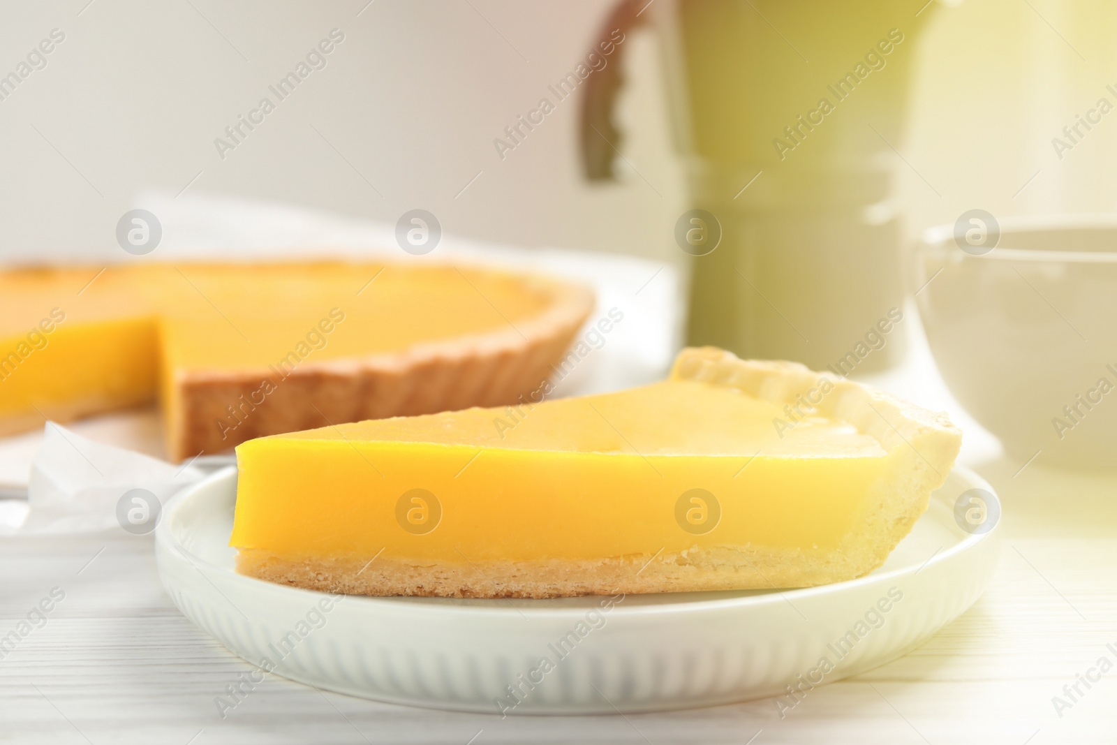 Photo of Slice of delicious homemade lemon pie on white wooden table