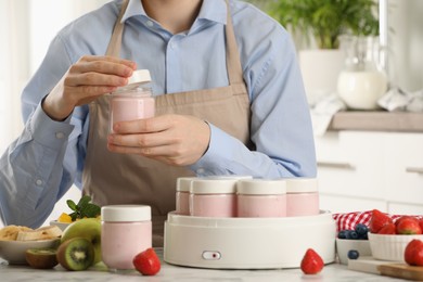 Photo of Woman making tasty yogurt at white marble table in kitchen, closeup