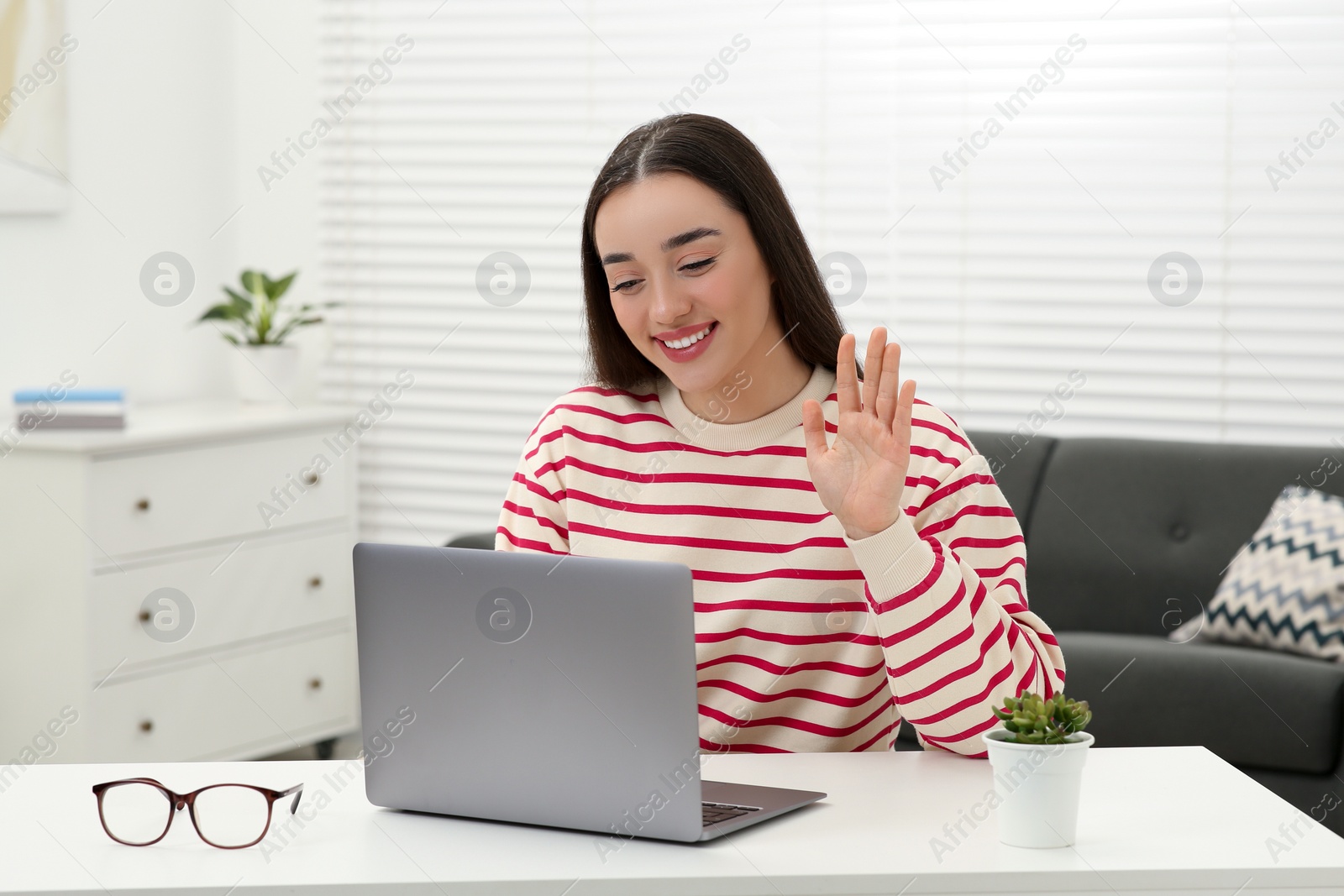 Photo of Woman having video chat via laptop at white table indoors