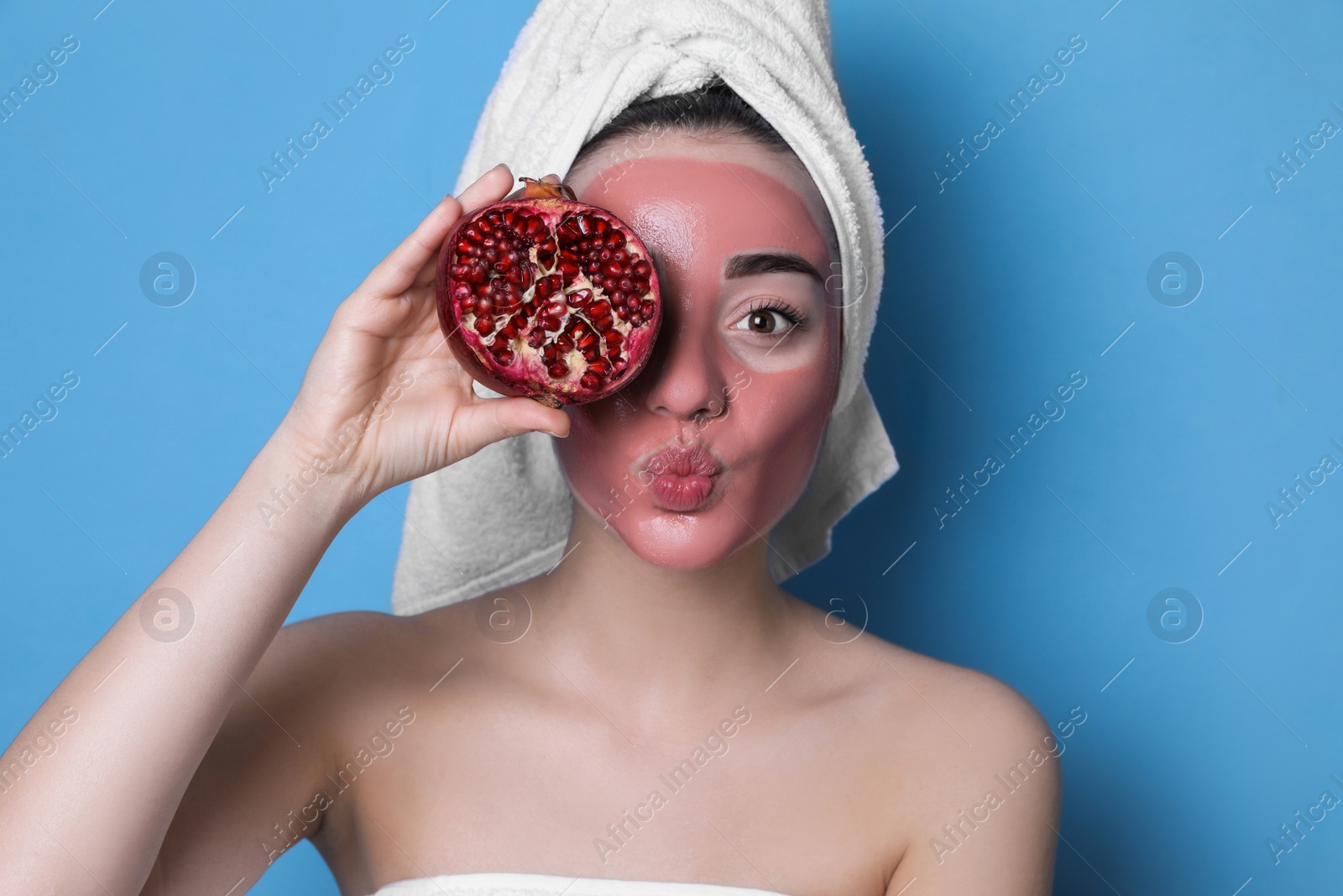 Photo of Woman with pomegranate face mask and fresh fruit on light blue background