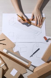 Photo of Woman creating packaging design at light wooden table, top view