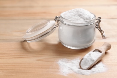 Photo of Jar and scoop with baking soda on wooden table