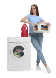 Beautiful young woman with laundry basket and detergent near washing machine on white background