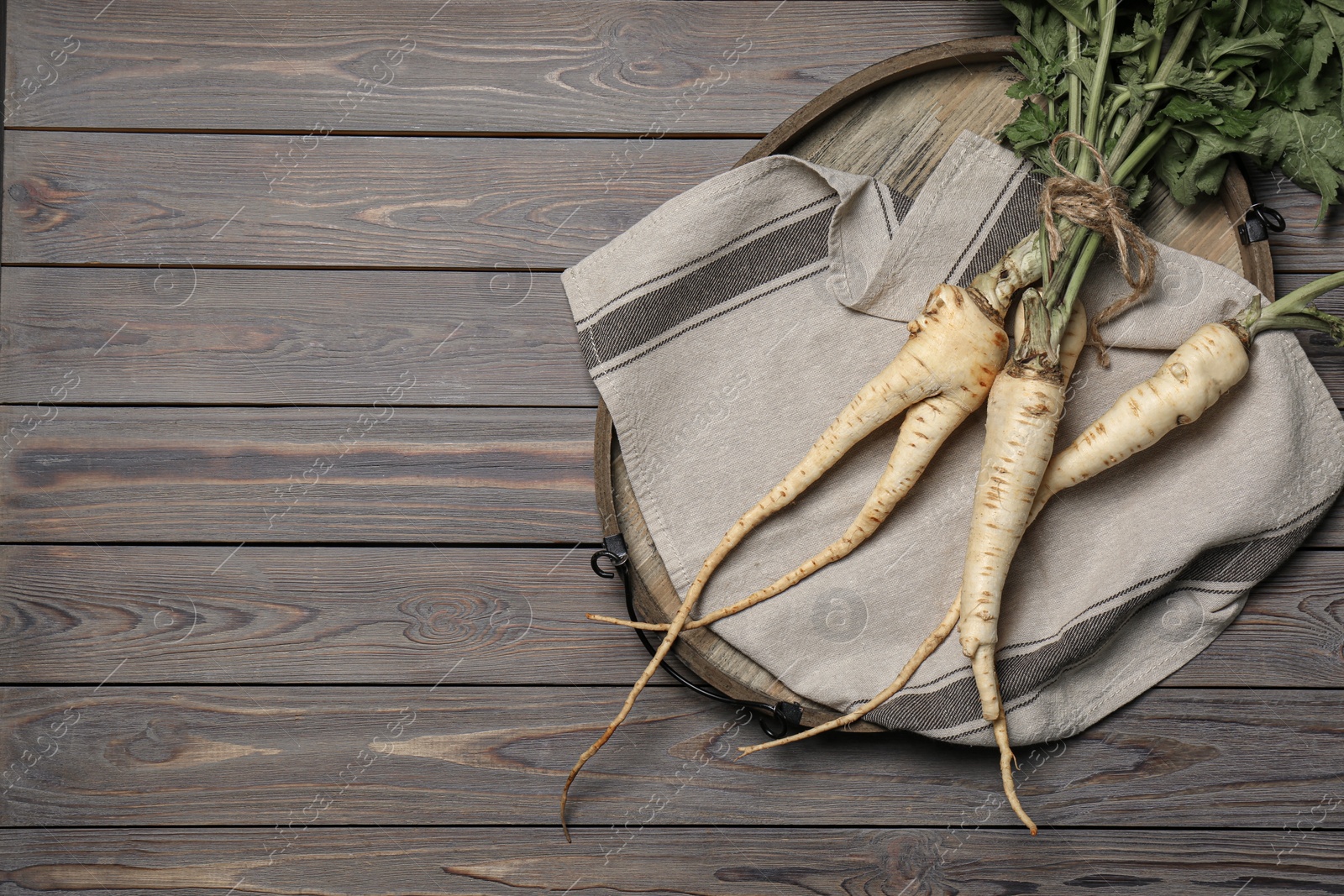 Photo of Tasty fresh ripe parsnips on grey wooden table, top view. Space for text