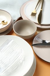 Photo of Clean plates, bowls, glass and cutlery on table