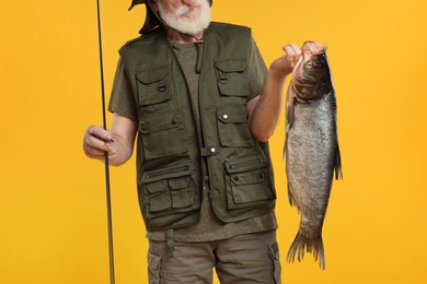 Fisherman with rod and catch on yellow background, closeup