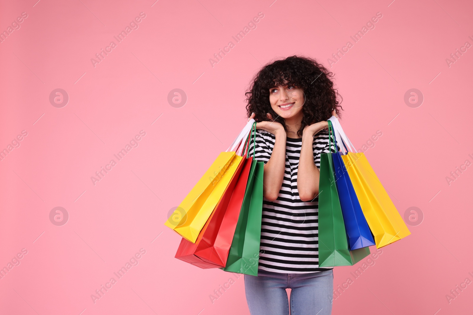 Photo of Happy young woman with shopping bags on pink background. Space for text