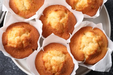 Delicious sweet muffins on black textured table, top view