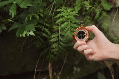 Photo of Traveler searching direction with compass in wilderness, closeup. Space for text