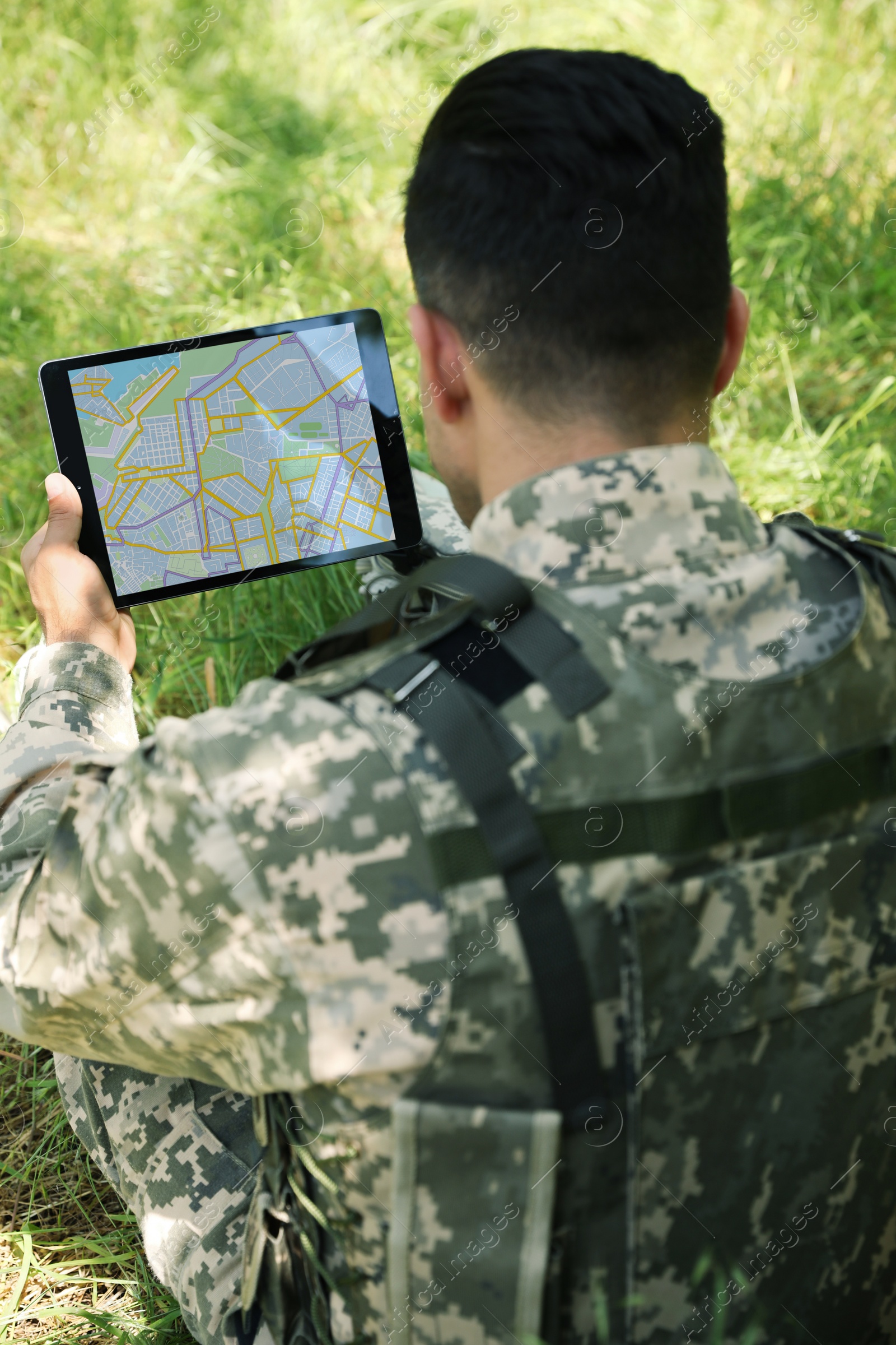 Photo of Soldier using tablet in forest, back view