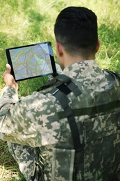 Photo of Soldier using tablet in forest, back view
